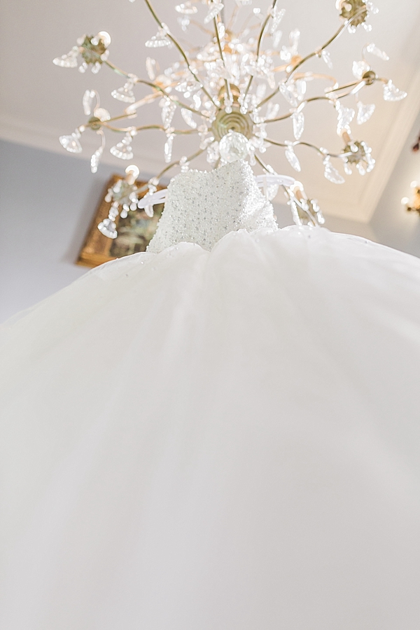 Bride's dress hanging from a chandelier in the bridal cottage at stanbrook abbey malvern worcester worcestershire wedding photographer image by hayley morris photography
