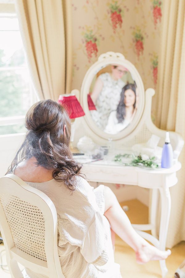 fine art wedding photography kateshill house italian wedding blessing photography west midlands - bride is having her hair styled ready for her wedding day, sat relaxed in front of a dressing table and mirror - image by hayley morris photography