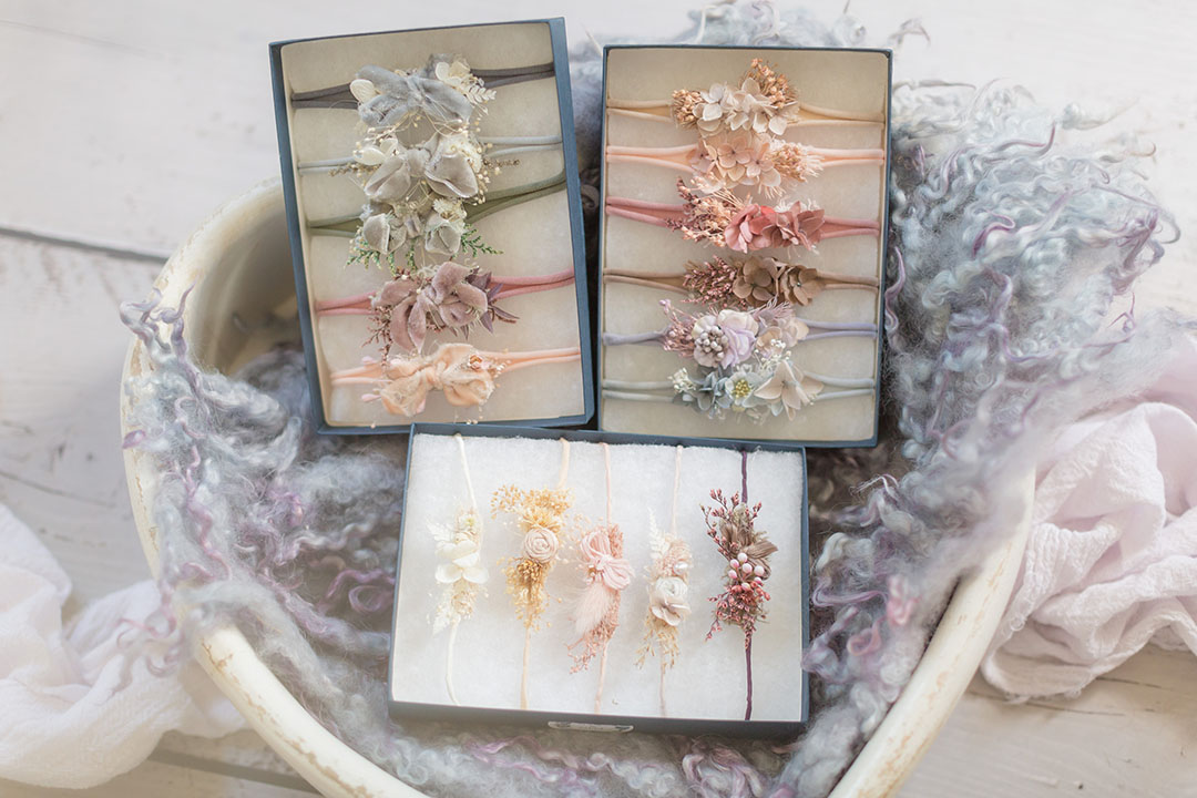 Boxes of newborn baby girl headbands on display and posed in a heart shape bowl along with coordinating wool layer on a wooden floor