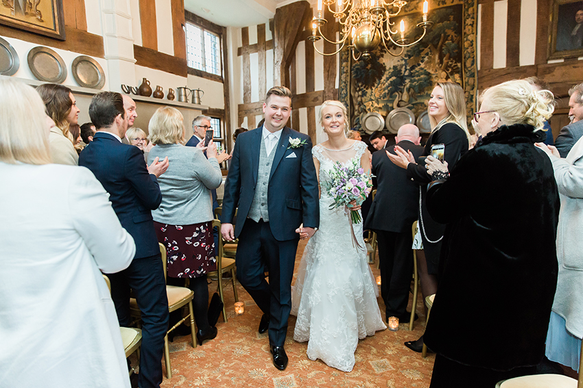 Married couple exiting the great hall in the manor house at birtsmorton court at their winter wedding