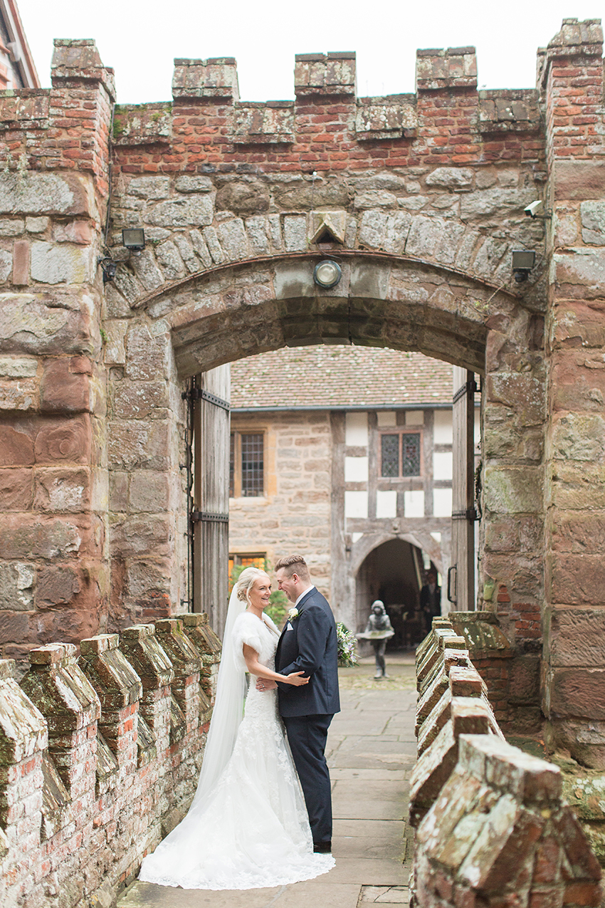 Couple stood on the gated bridge over the moat at birtsmorton court shortly after their wedding