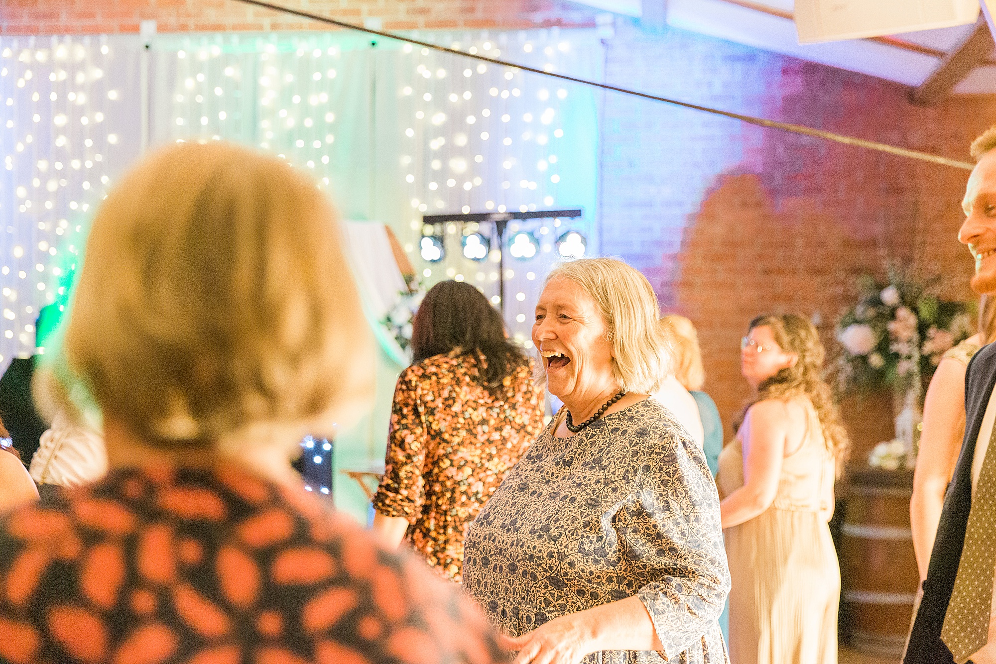 image shows guests dancing and singing at a wedding reception in the evening, 
