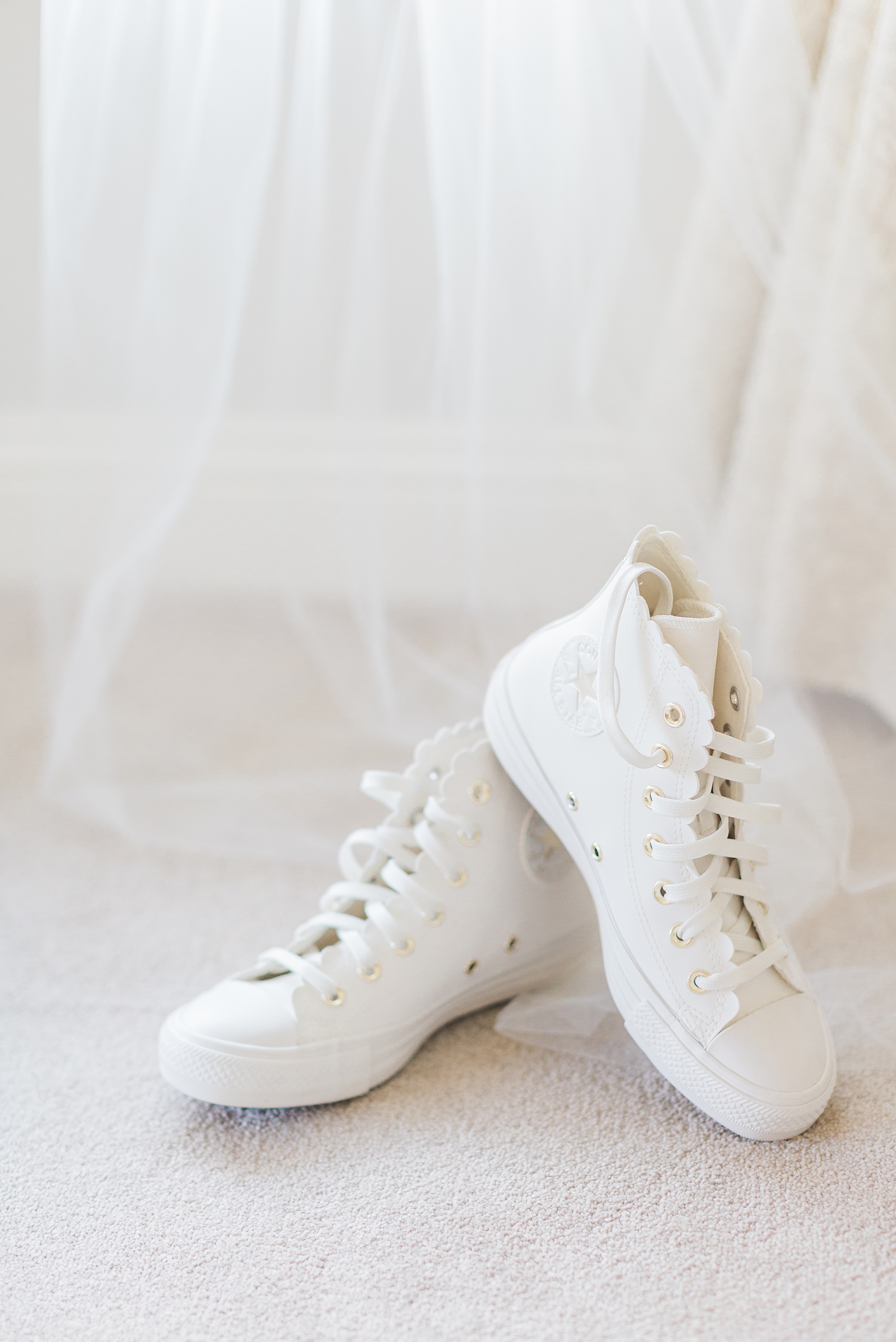 Photo of white converse styled for a wedding. Photo of the converse are taken against a white veil at cider mill barns