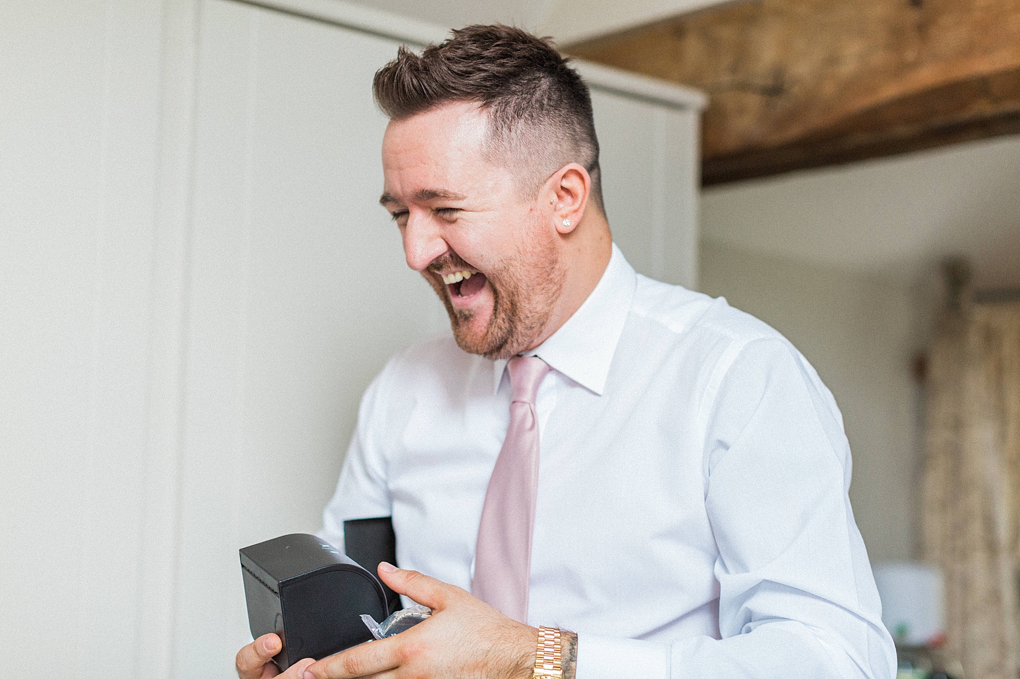 groom on his wedding morning opening a gift from his wife to be - image shows his surprise and expression on his face after opening the gift