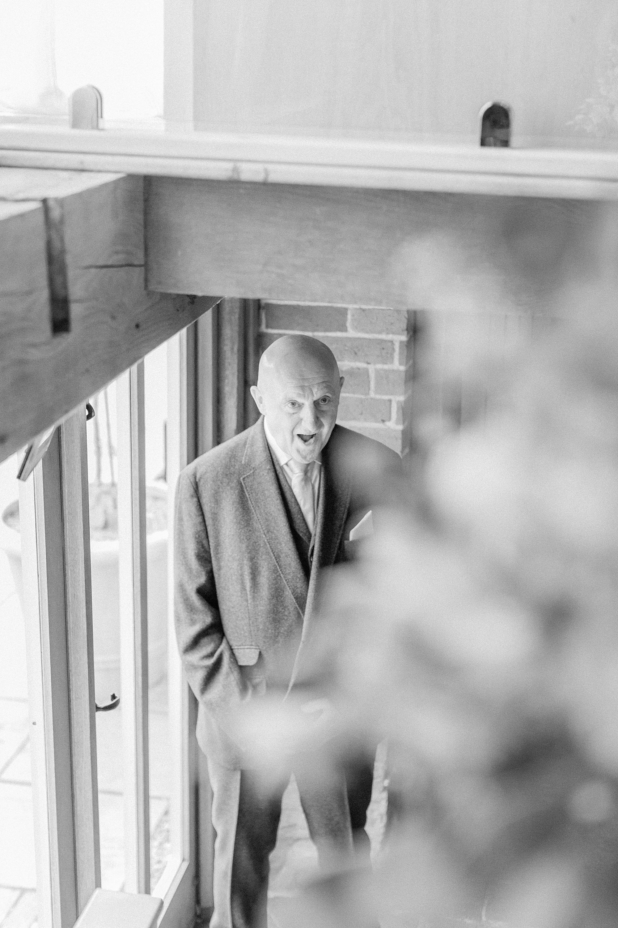 Photo shows the ack of the bride walking down the stairs at curradine barns and her dad is stood at the bottom of the stairs waiting to greet her 