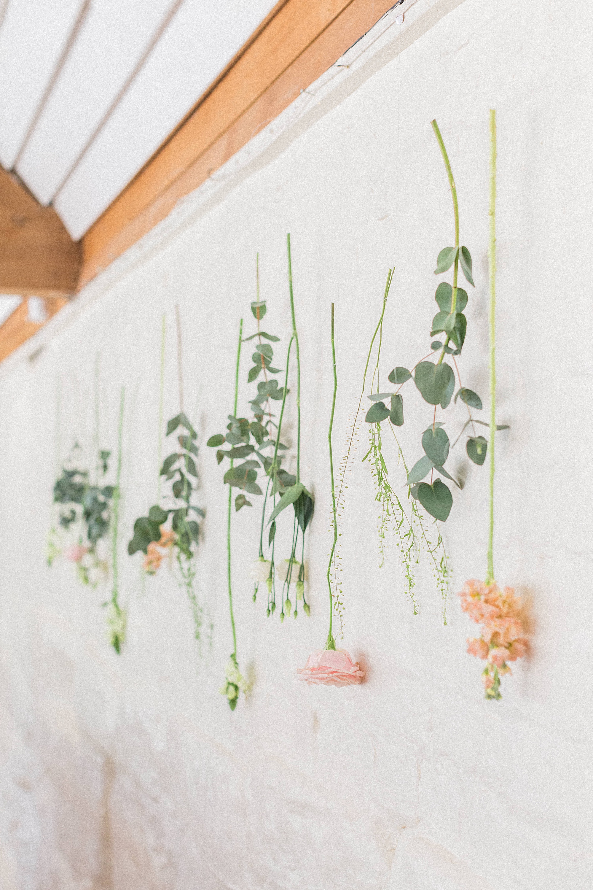 photo of a floral display with flowers hanging along a wall at a wedding reception 