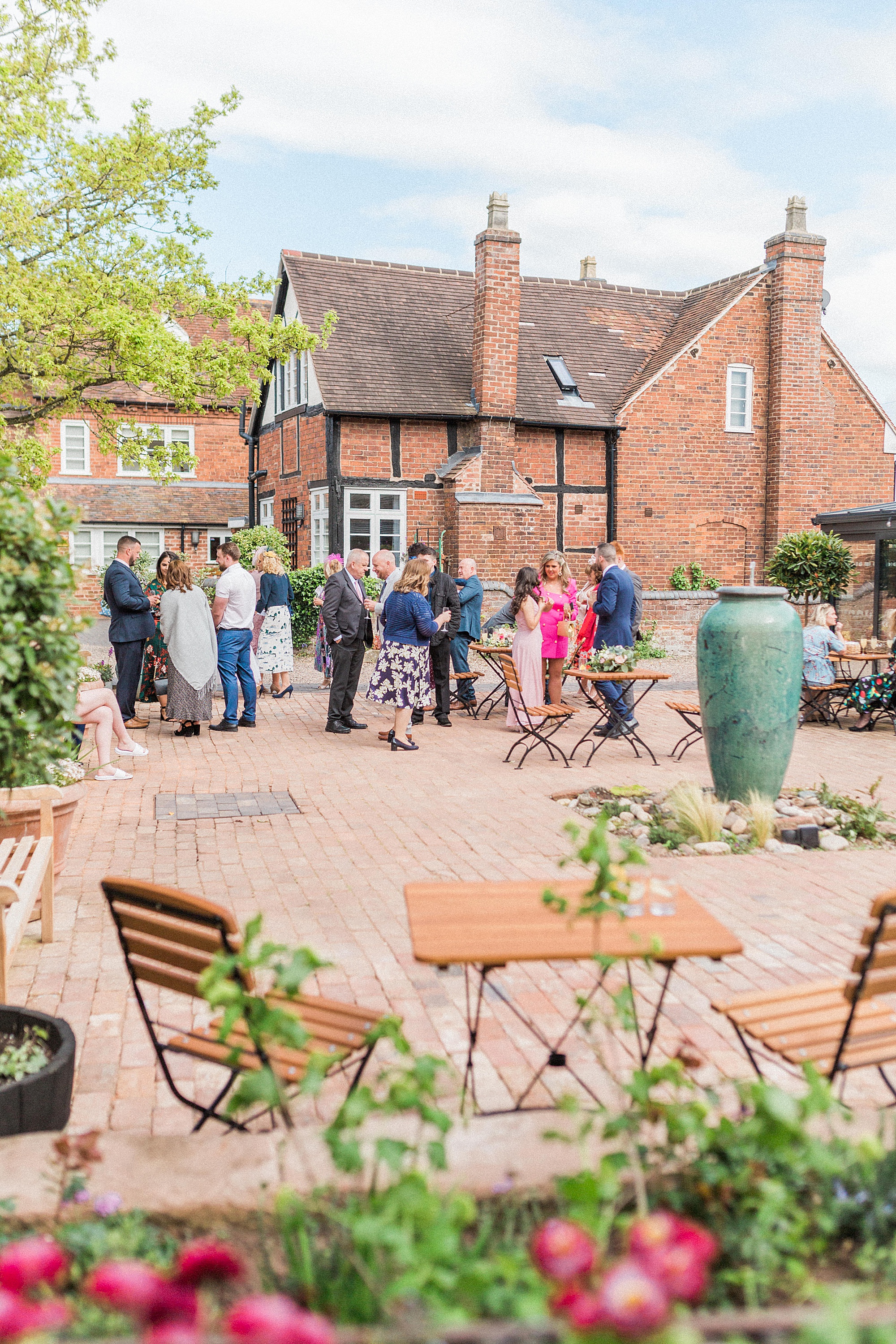 photo of the courtyard at curradine barns during a drinks reception with guests drinking, eating canapes and talking with each other