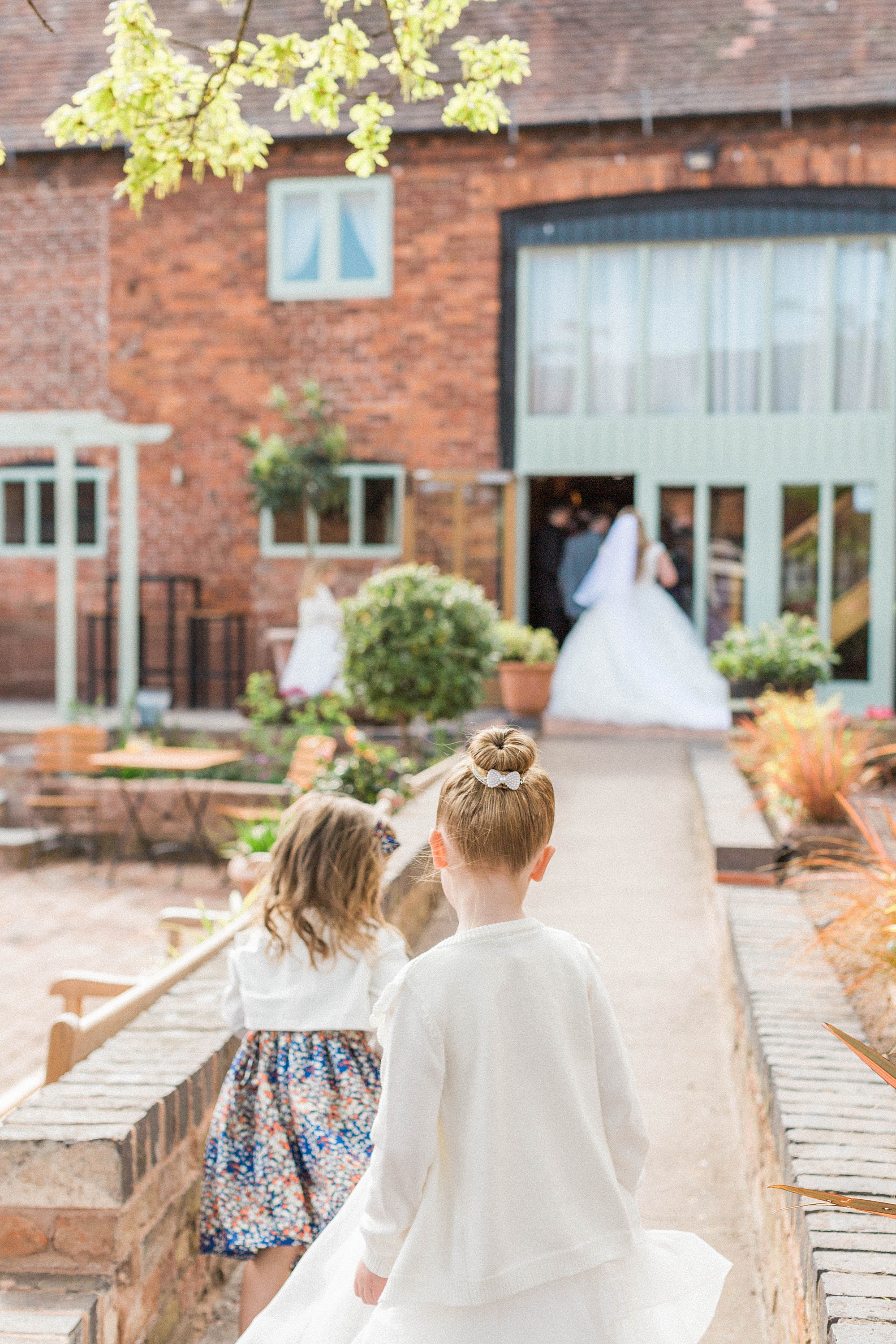 photo shows two children playing on a path at curradine barns with a bride in the background on her wedding day 