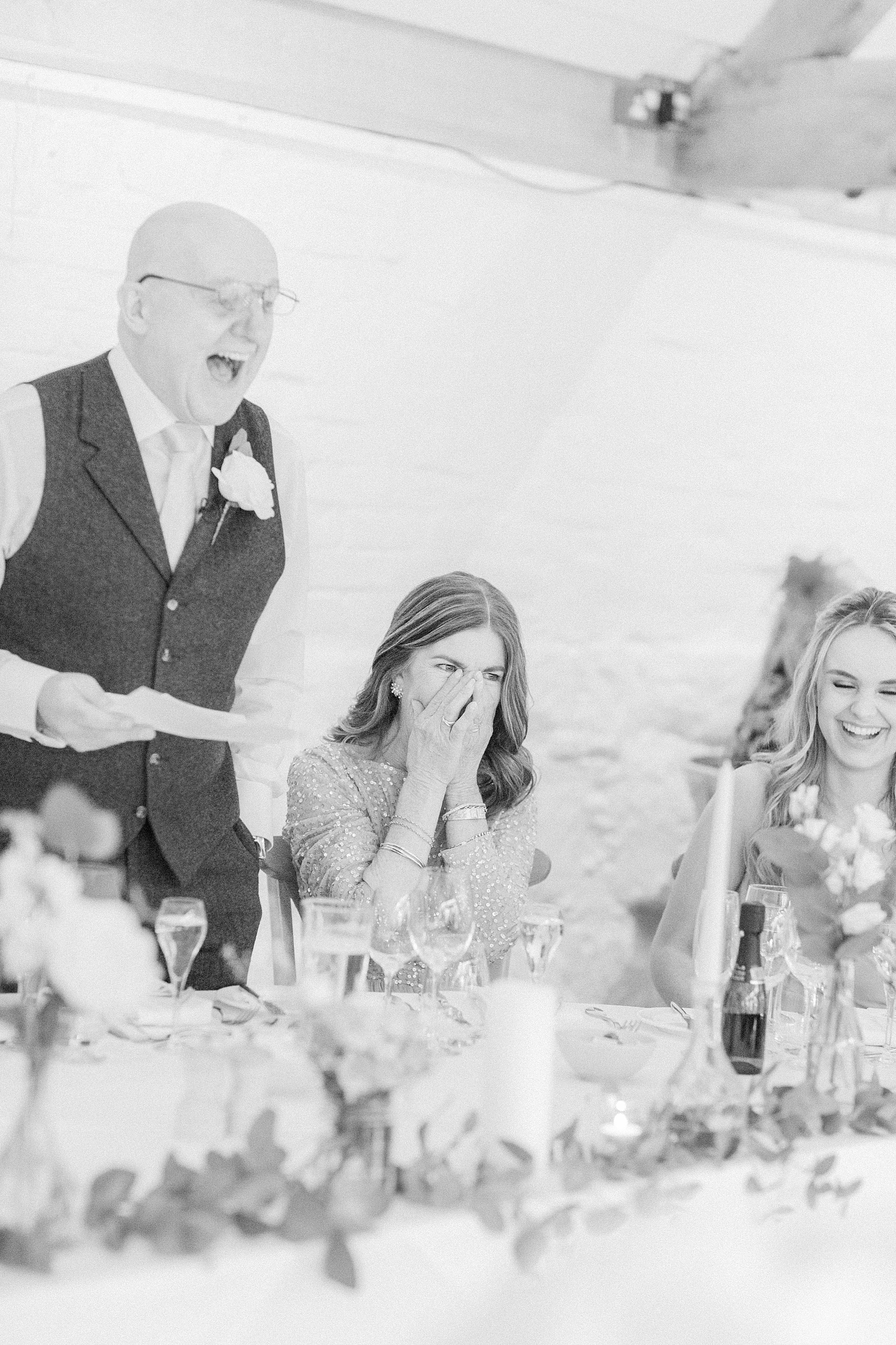 photo of the speech at a wedding by the father of the bride and his wife's and bridesmaid's reaction