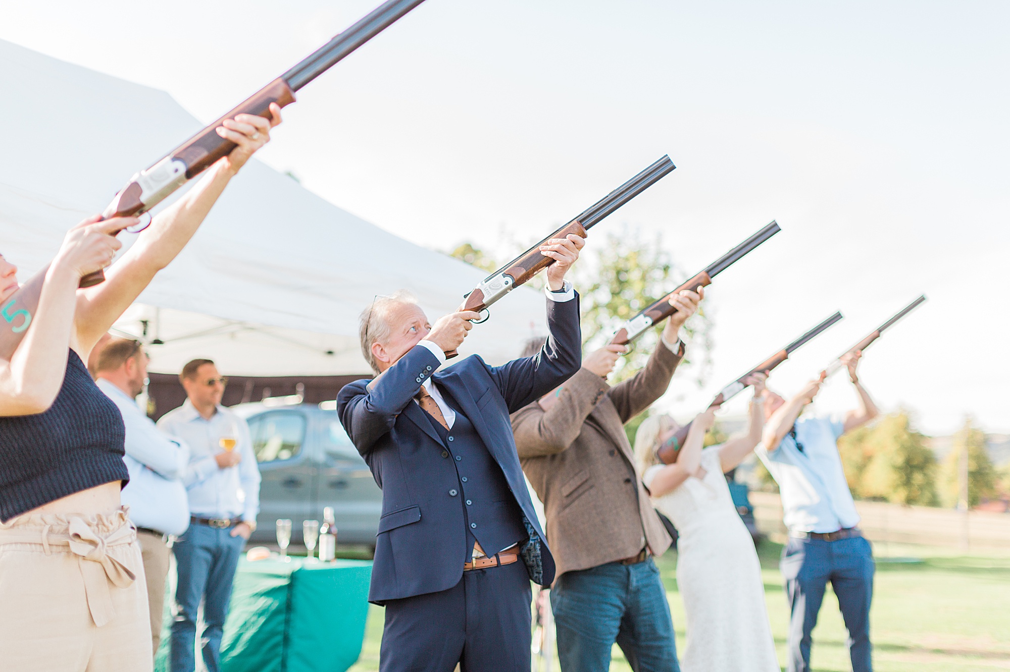 image shows guests holding clay pigeon shooting rifles playing laser clay pigeon shooting at a wedding in the cotswolds 