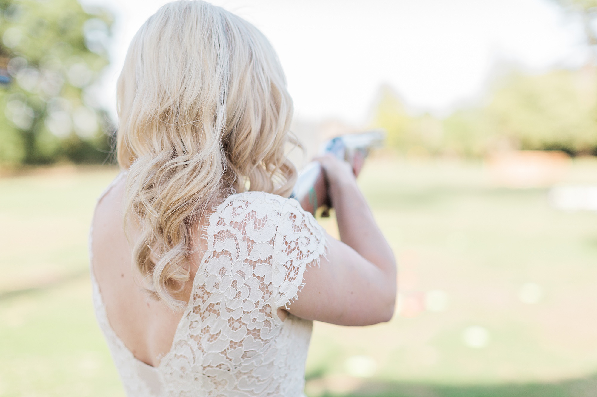 image of a bride holding a laser clay pigeon shooting rifle at her wedding reception in the cotswolds 