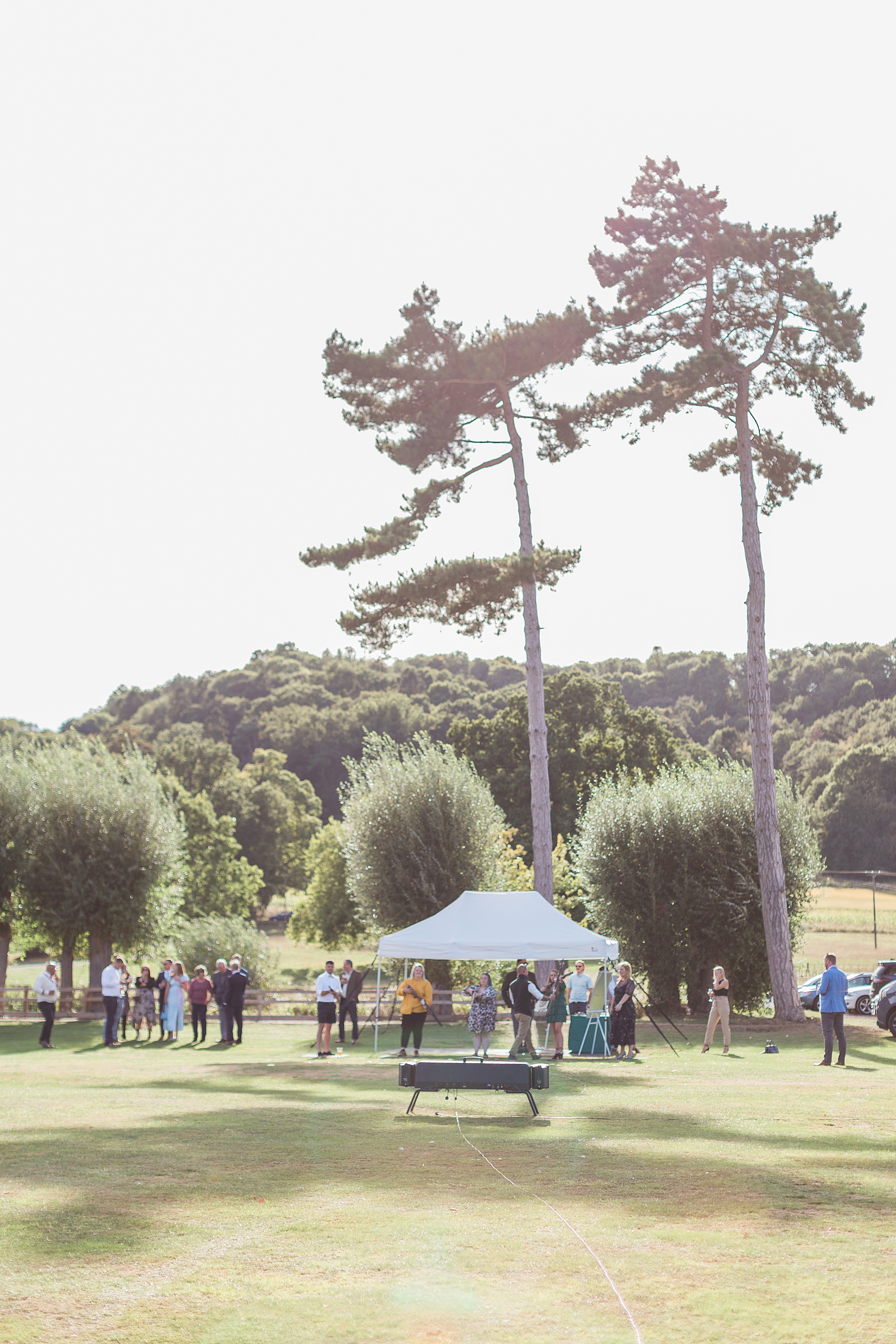 photo of the grounds at dumbleton cricket club on an early autumn wedding day. Image shows guests enjoying laser clay pigeon shooting