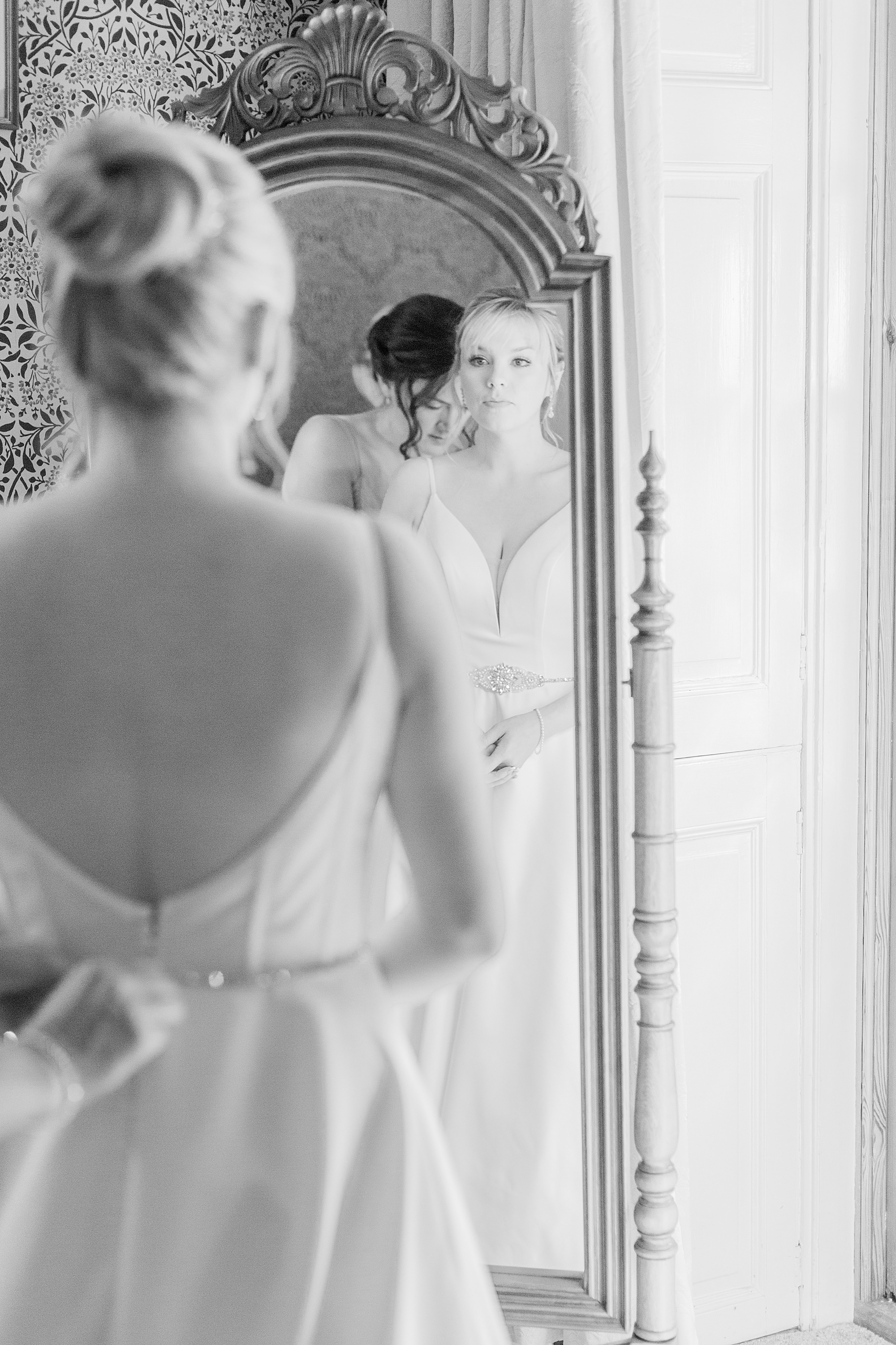 Photo of a bride looking at herself in the mirror on the morning of her wedding and getting dressed