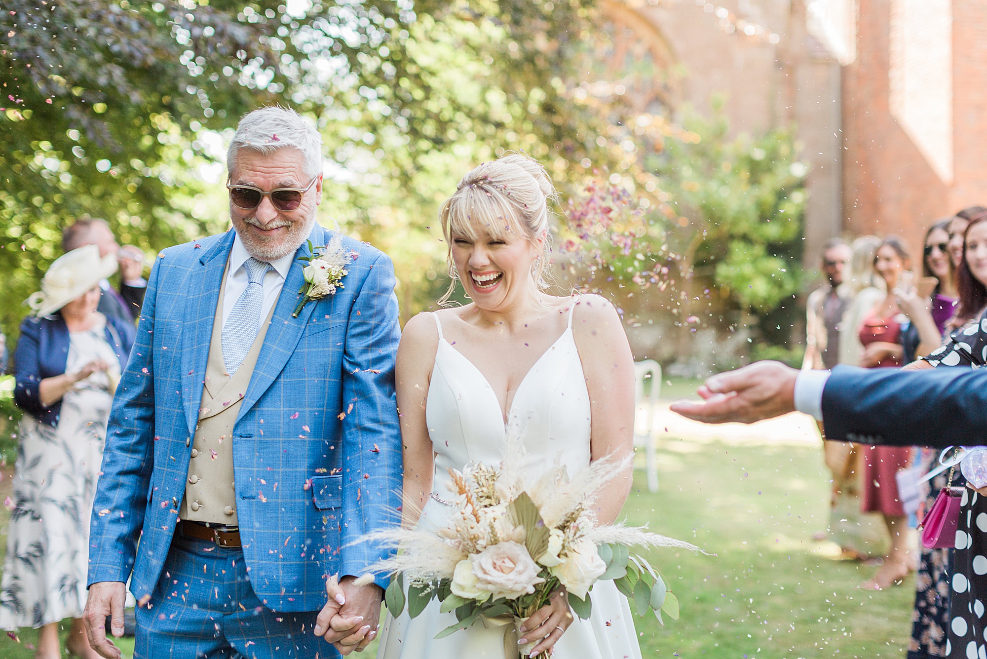 bride and groom walking under confetti in the grounds of grafton manor 