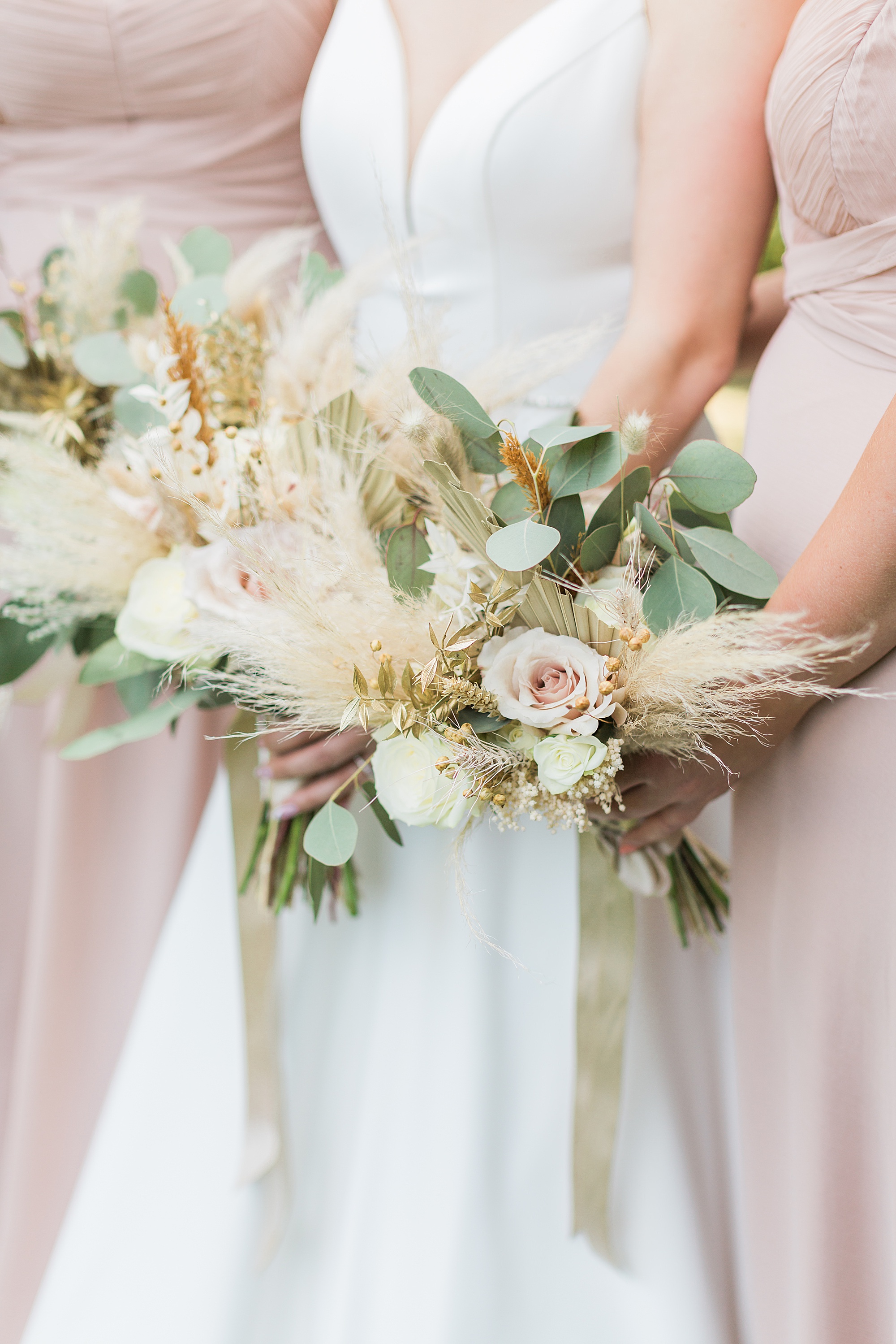 photo shows a bride and bridesmaids holding their gorgeous bouquets against their dresses. The photo doesn't show their faces but the focal point of this photo is the bouquets and dresses 