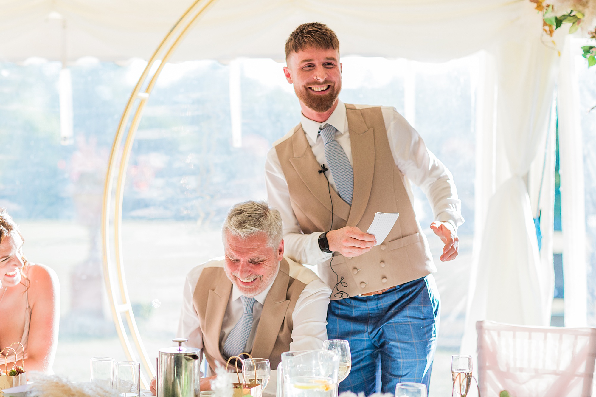Photo shows the groom and his best man laughing/joking together during the best man's speech at a wedding 