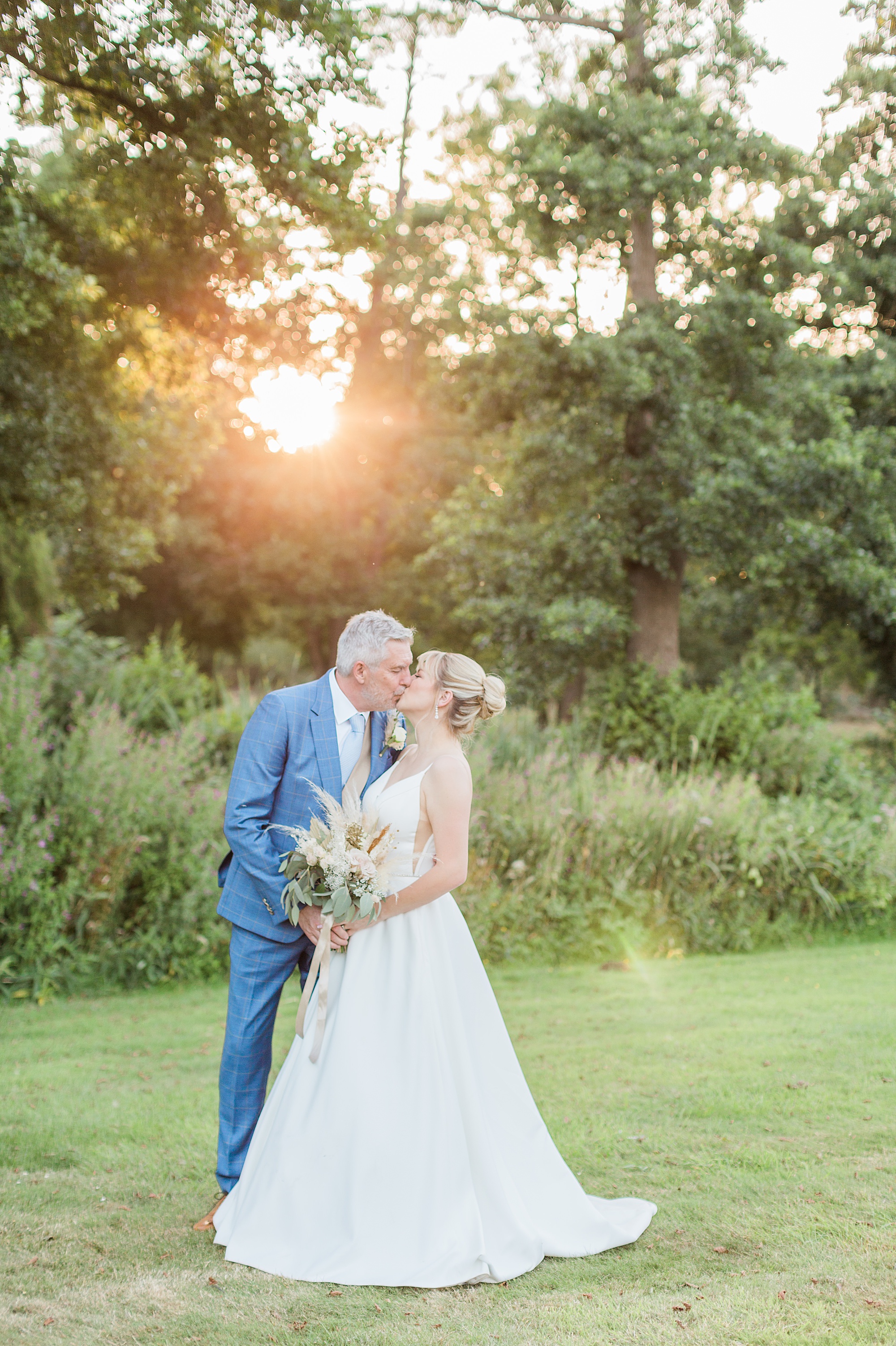 photo of a bride and groom kissing in the sunset with the lake and grounds of grafton manor behind them