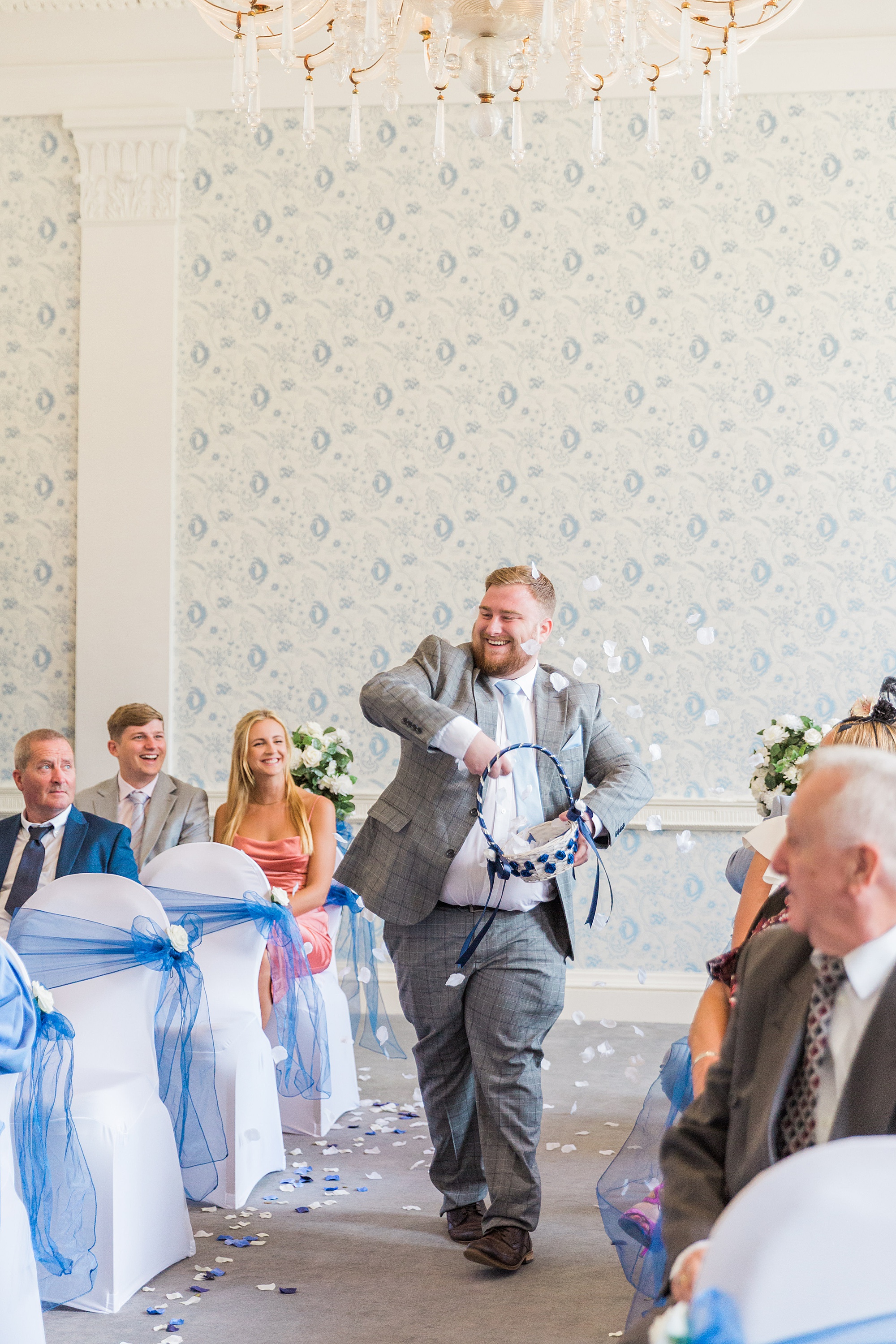 photo showing a flower man skipping down the aisle at a wedding throwing confetti from a basket at himley hall
