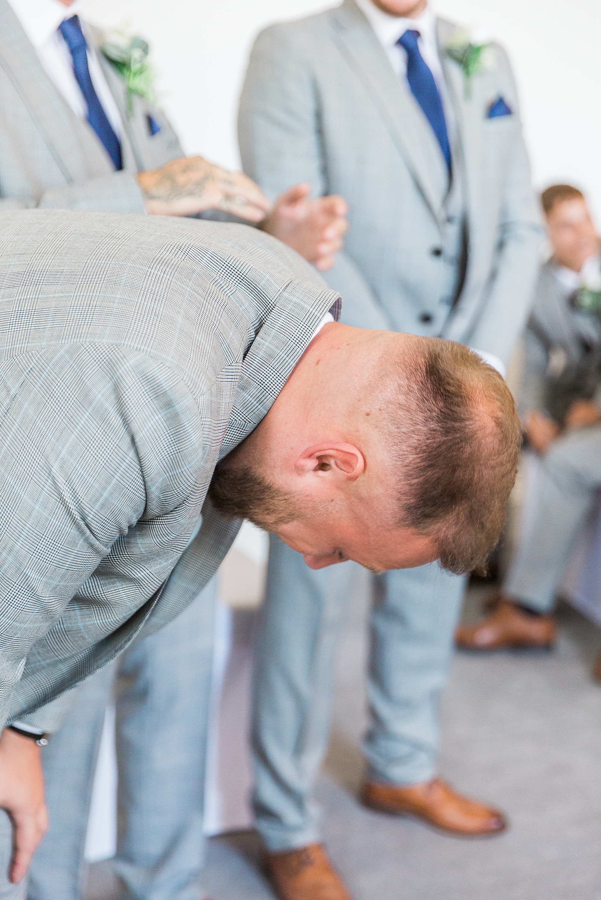 photo of a groom's reaction at the start of his wedding, the groom is bent over towards the floor with emotion