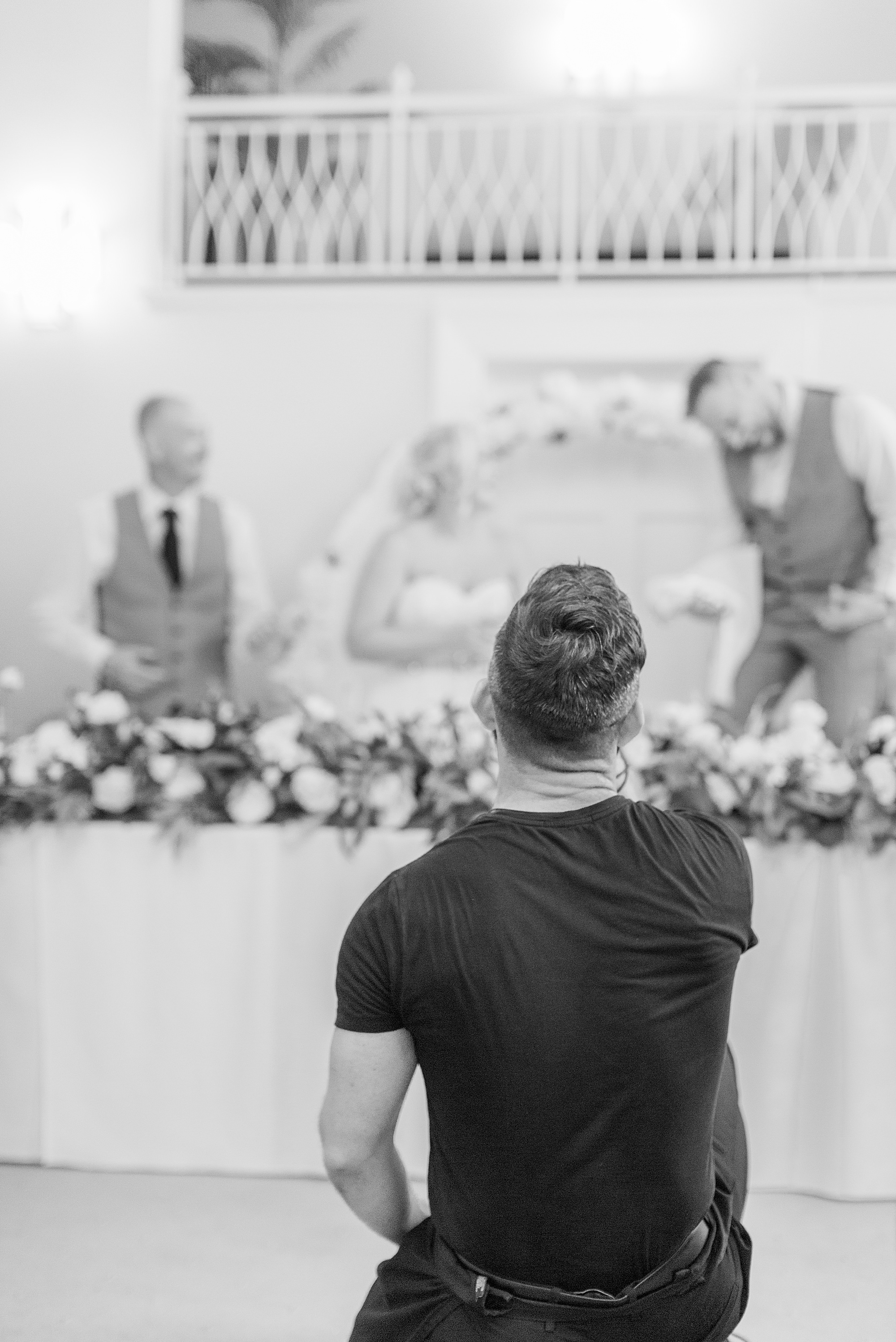 photo of a singing waiter kneeling performing at a wedding with the groom and bride in the background singing and dancing