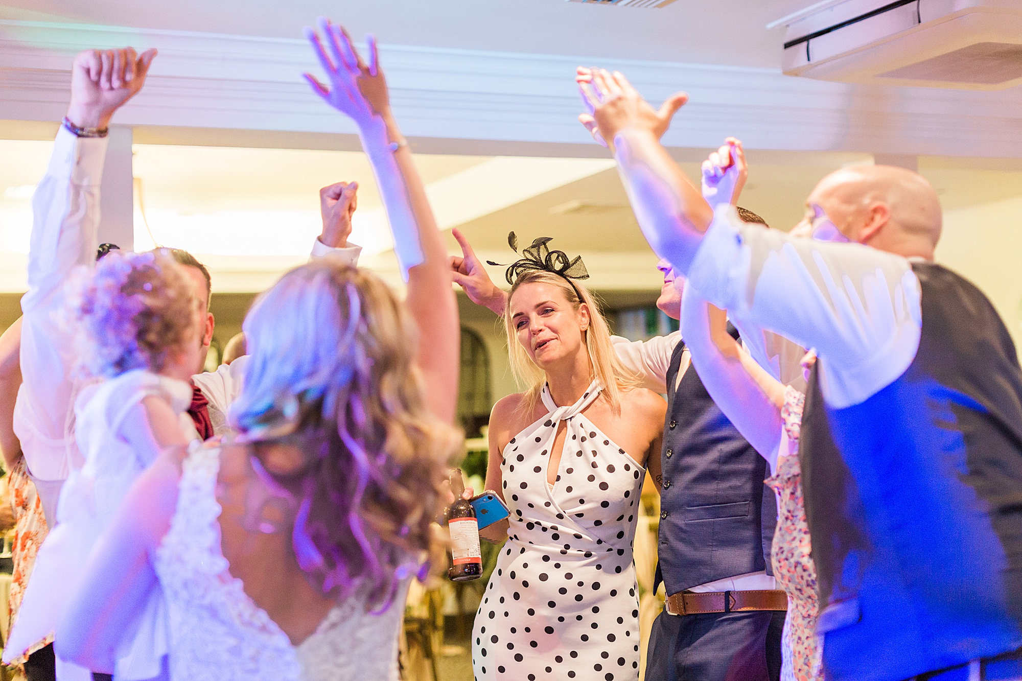 image shows guests dancing and singing at a wedding reception in the evening, they've got their hands in the air