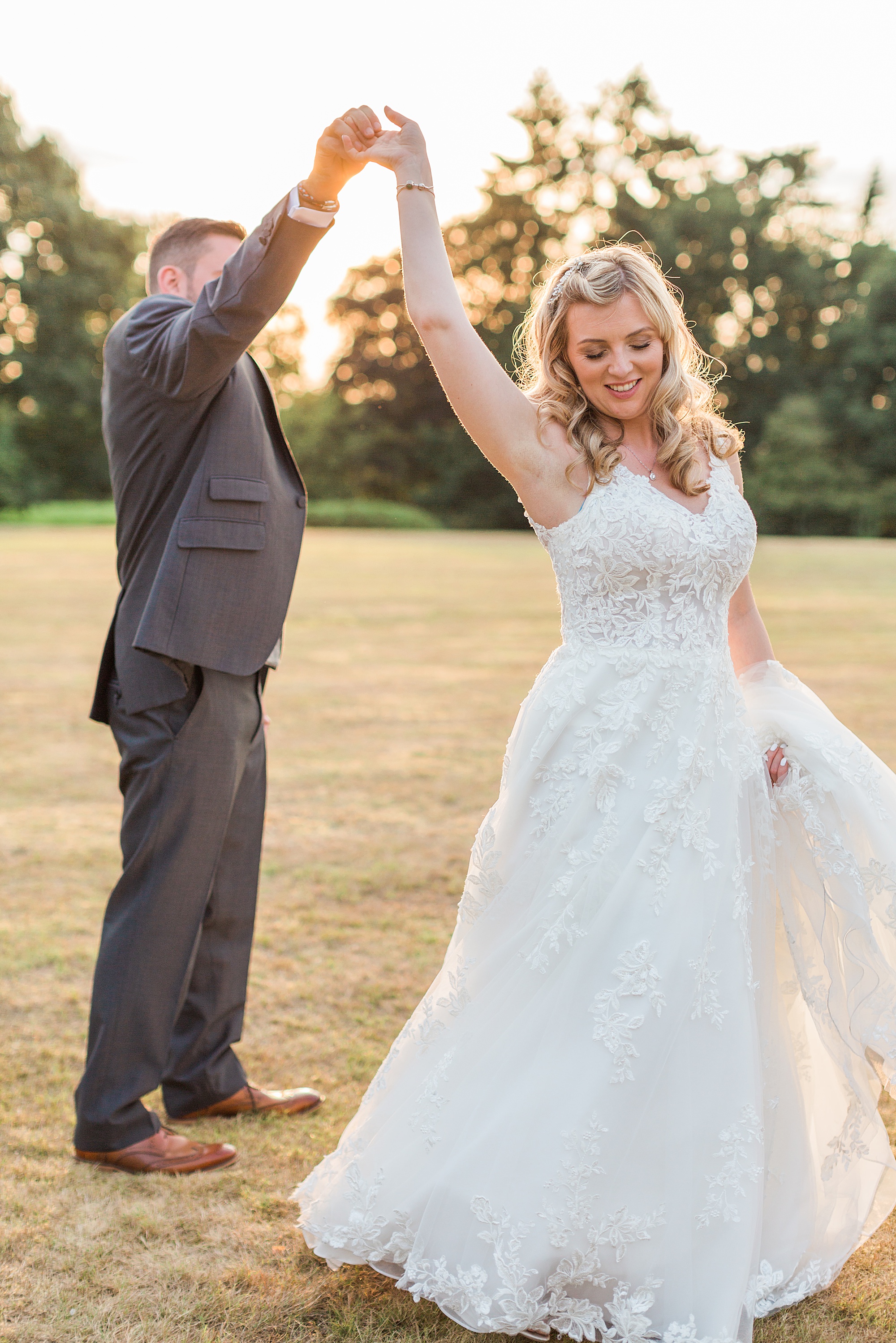 photo of a bride and groom in the sunset on the lawn at hogarths stone manor, the groom is spinning the bride around with his hand holding hers above her head 