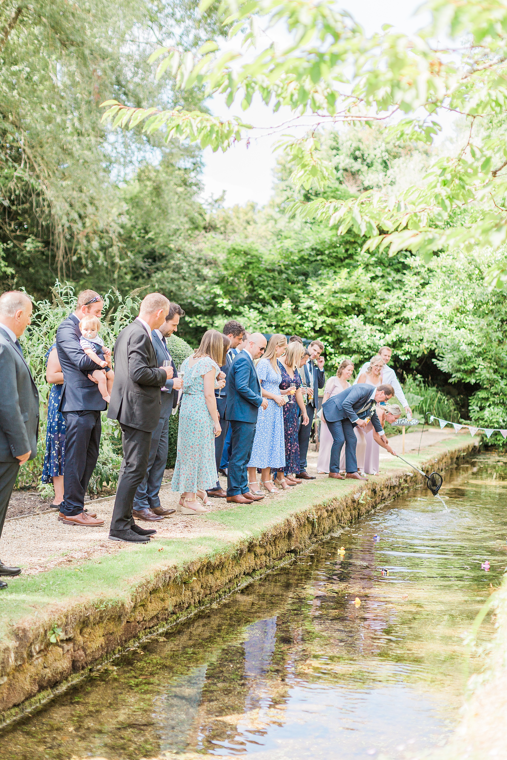 photo of guests at the swan at bibury in the cotswolds playing a game of racing ducks on the stream at the venue