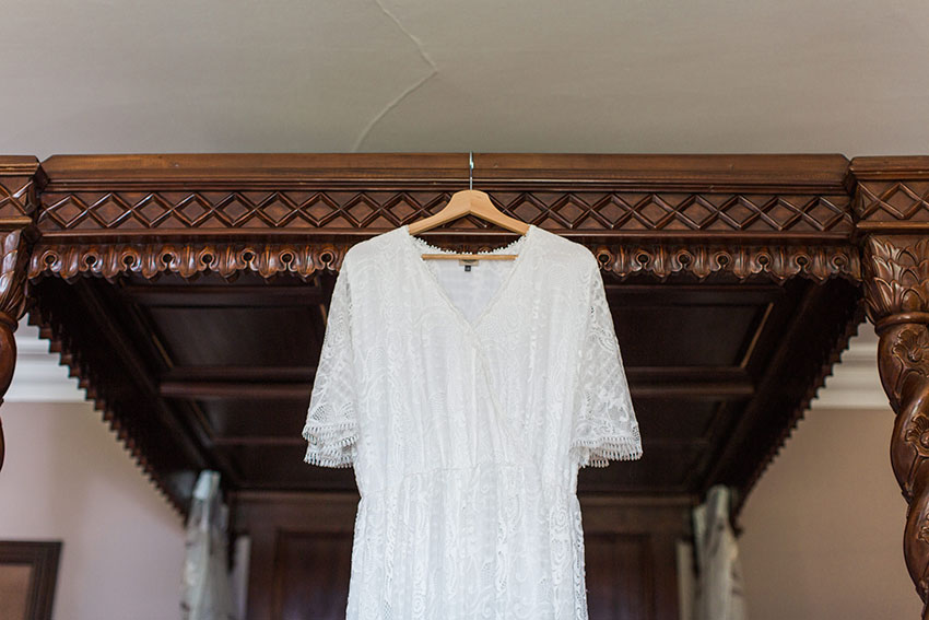 Lace bridal dress hanging on a four poster bed in the bridal suite of homme house