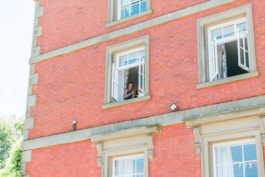 bridesmaids looking out of the window of homme house as the red arrows flew over