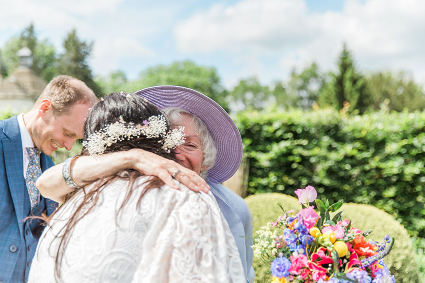 bride hugging a family member tightly at her outdoor wedding ceremony