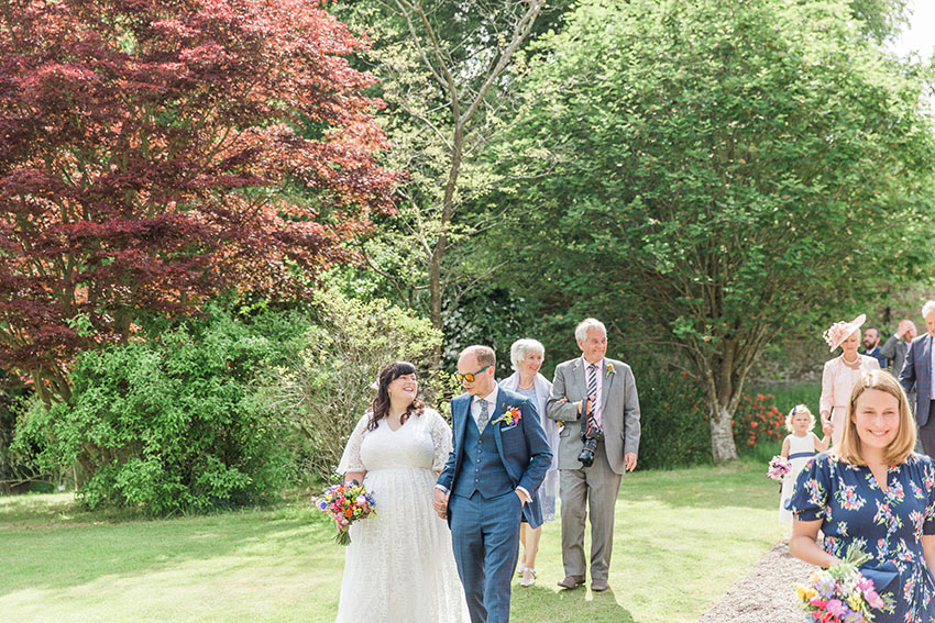 bride groom and guests walking outdoors from their wedding ceremony towards their outdoor drinks reception on the lawn at homme house