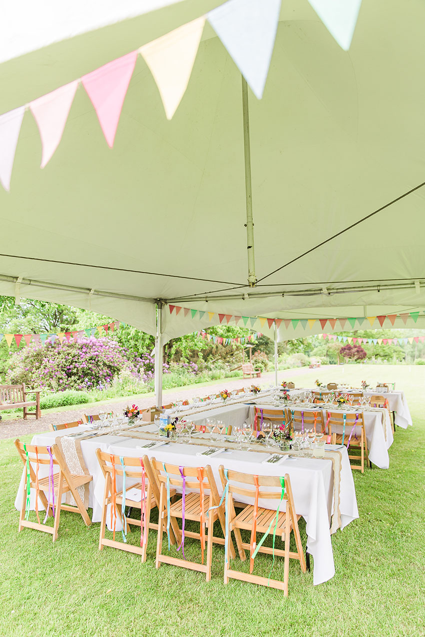 wedding reception detail in a sideless marquee set for an outdoors reception, lots of colour, festival and colours themed
