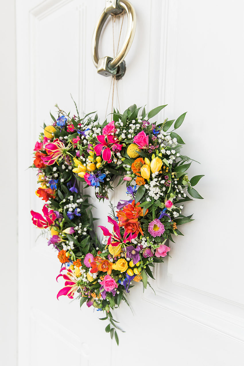 colourful floral wreath at a wedding reception hanging from the door at the venue