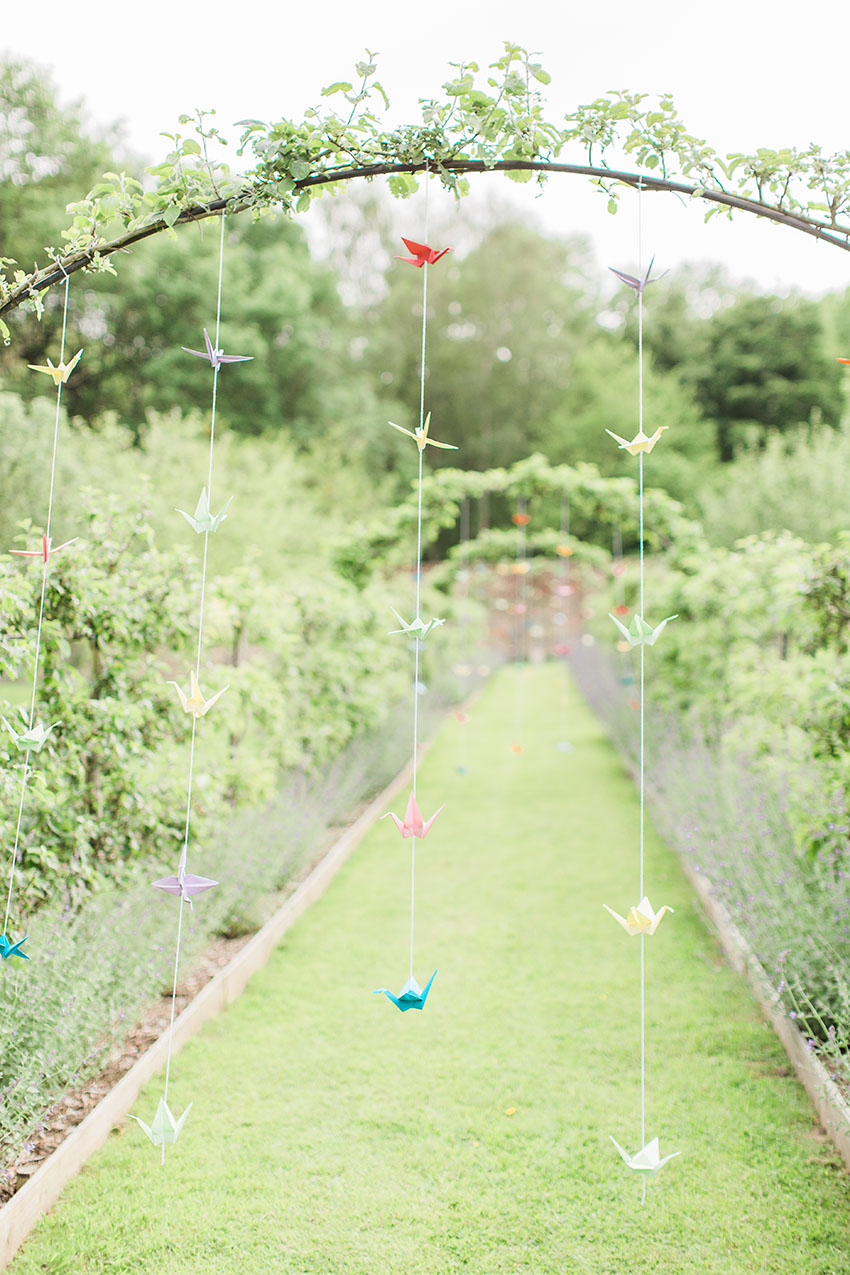 close up photo of the origami cranes hanging ing the orchard of the gardens at homme house